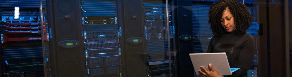 pexels-photo-1181354-1181354 A female engineer using a laptop while monitoring data servers in a modern server room.